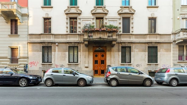 A building with a central entrance, multiple windows, and balconies with plants. - GuestHost - APT X3 Loreto Città Studi M1/M2 & C.so Buenos Aires (Milano)