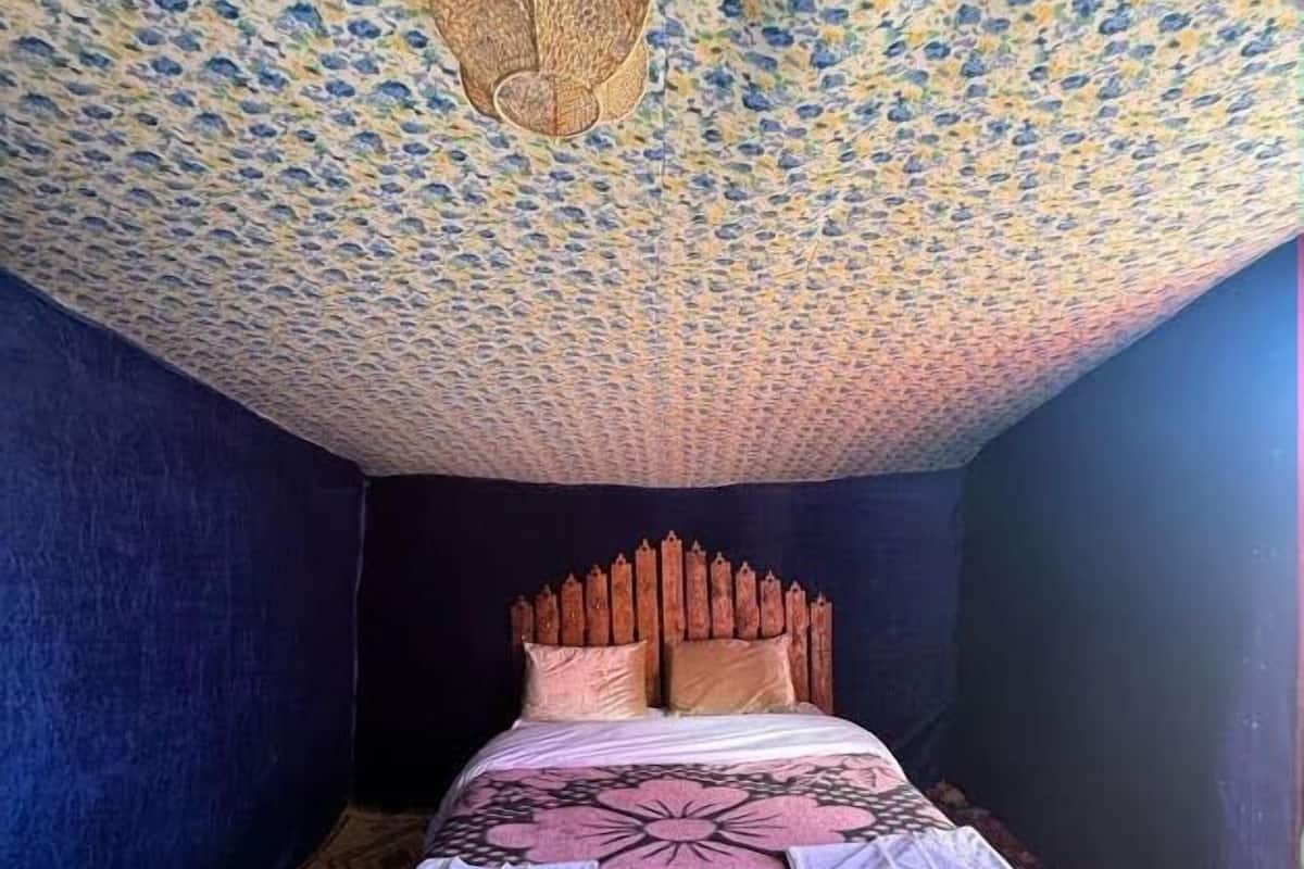 Een slaapkamer met een patroonplafond, een houten hoofdbord en een bloemenbedovertrek.