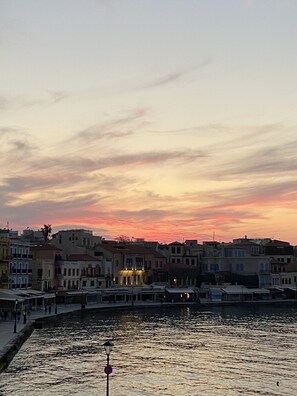 A waterfront cityscape at sunset with buildings along the riverbank.