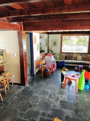 Una habitación acogedora con suelo de piedra, vigas de madera, un sofá, una mesita y varios juguetes infantiles.