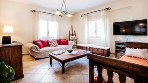 Un salon bien éclairé, avec un canapé, une table basse, un téléviseur et un tableau accroché au mur.