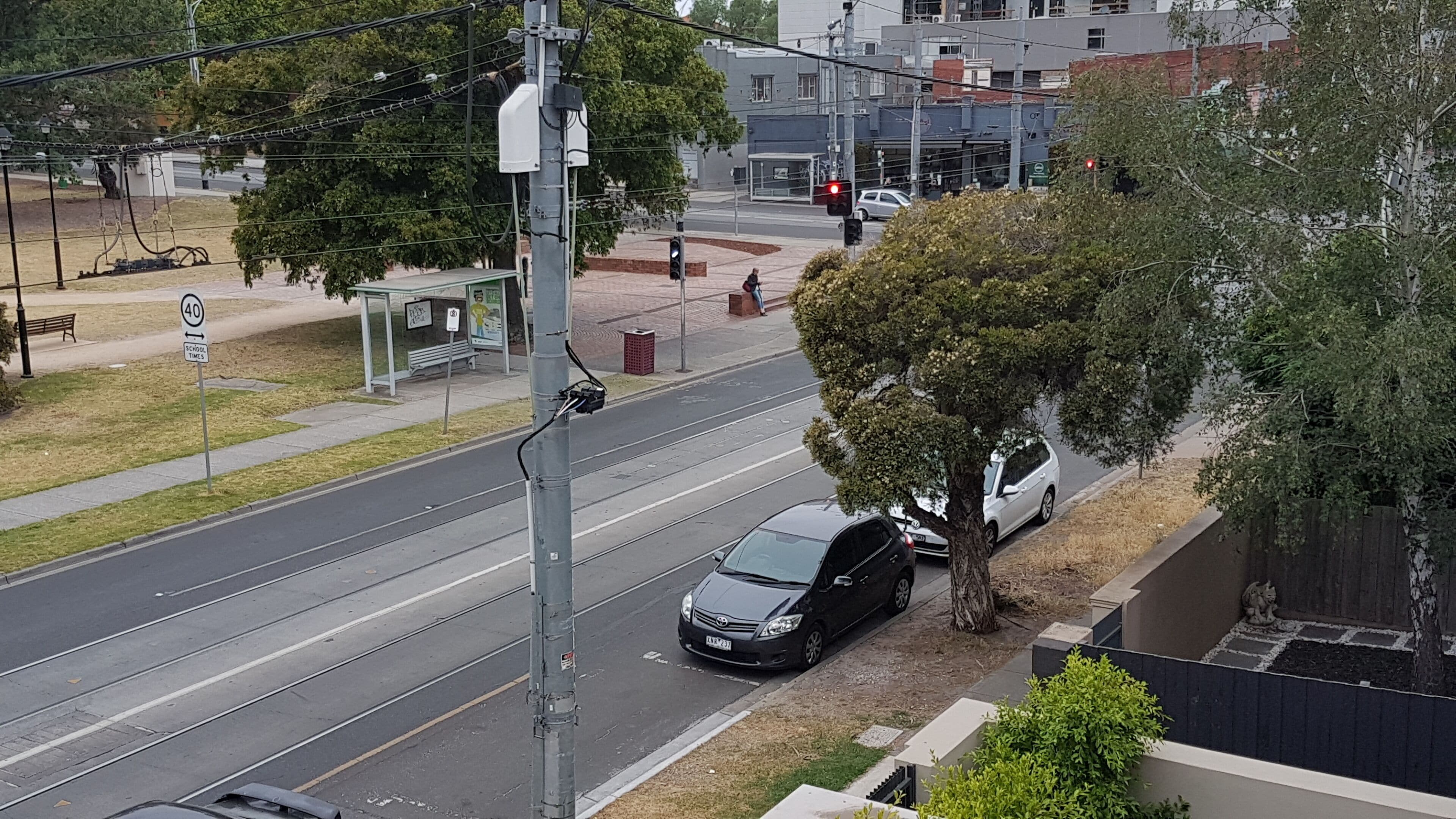 Straßenansicht mit Straßenbahnlinie, Bushaltestelle und Fußgängerüberweg.
