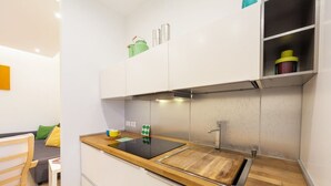 A compact kitchen with a wooden countertop, a built-in stove, and white cabinets.