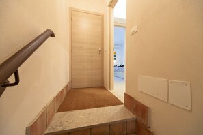 A narrow hallway with a wooden door, a carpeted step, and a handrail. - This bright 50sqm apartment with balcony can accommodate up to 4 people. Located on the first floor, without lift, of a typical Syracusan building, the apartment is located a few steps away from Temple of Apollo and Ortigia Market.The property is located (Siracusa)