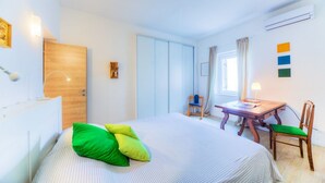 A hotel room with a bed, a desk, a chair, and a wardrobe.