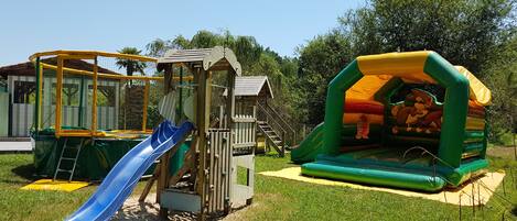 A playground with a slide, climbing structure, and inflatable bounce house.