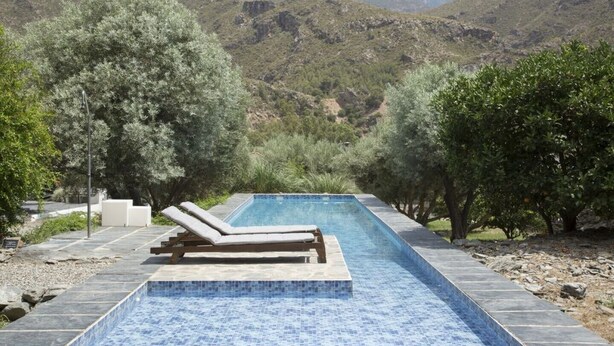 A rectangular pool with a tiled edge, surrounded by stone steps and two lounge chairs. - Villa with Private Pool, Surrounded by Mountains, Olive, Walnut and Orange Trees (Orgiva)