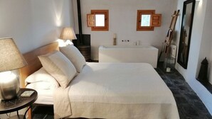 A bedroom with a bed, bedside table, lamp, and a window with shutters. - Villa with Private Pool, Surrounded by Mountains, Olive, Walnut and Orange Trees (Orgiva)