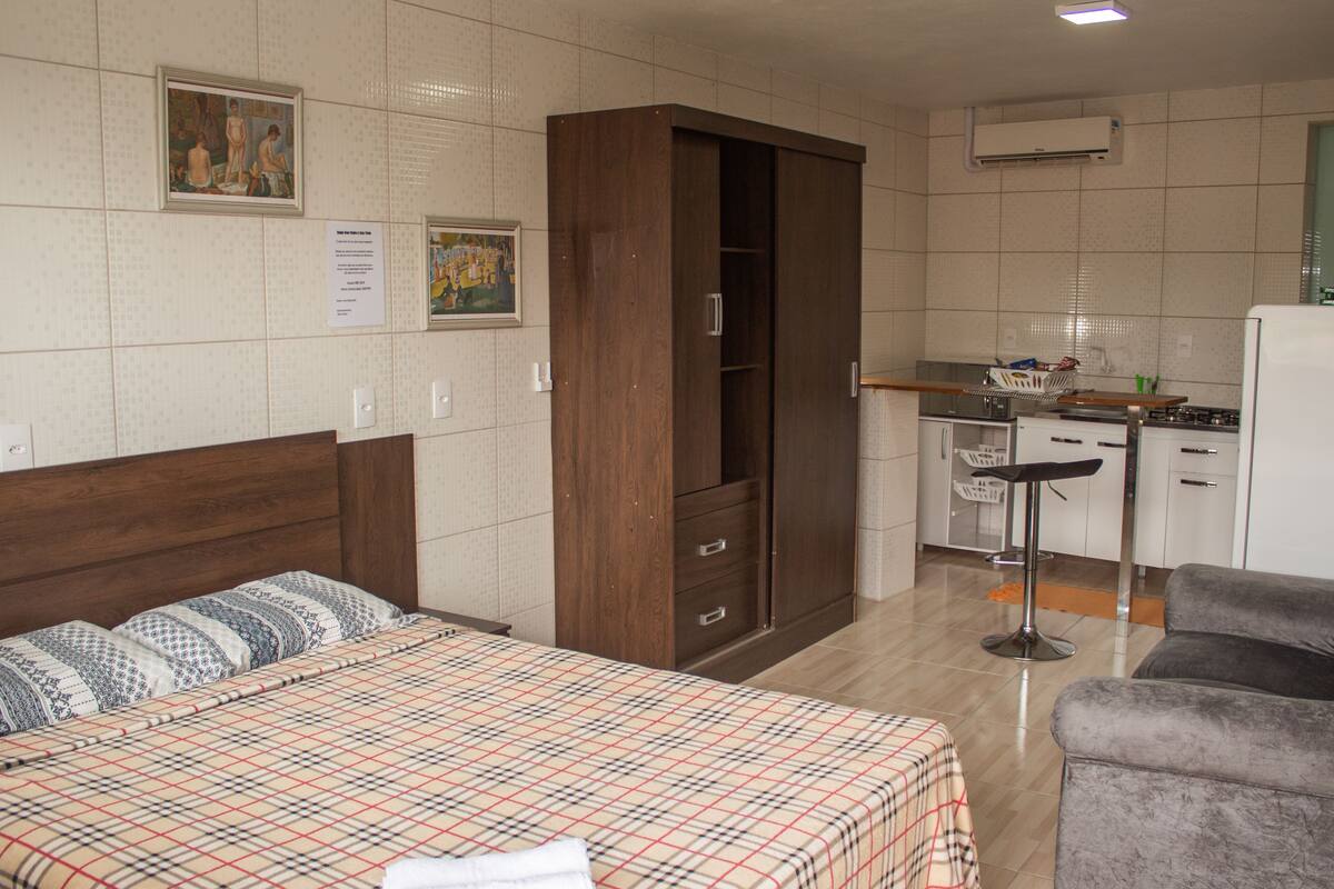 Una habitación de hotel con cama, armario, kitchenette y zona de estar.