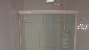 Un baño con ducha de vidrio, inodoro y lavamanos con toalla.
