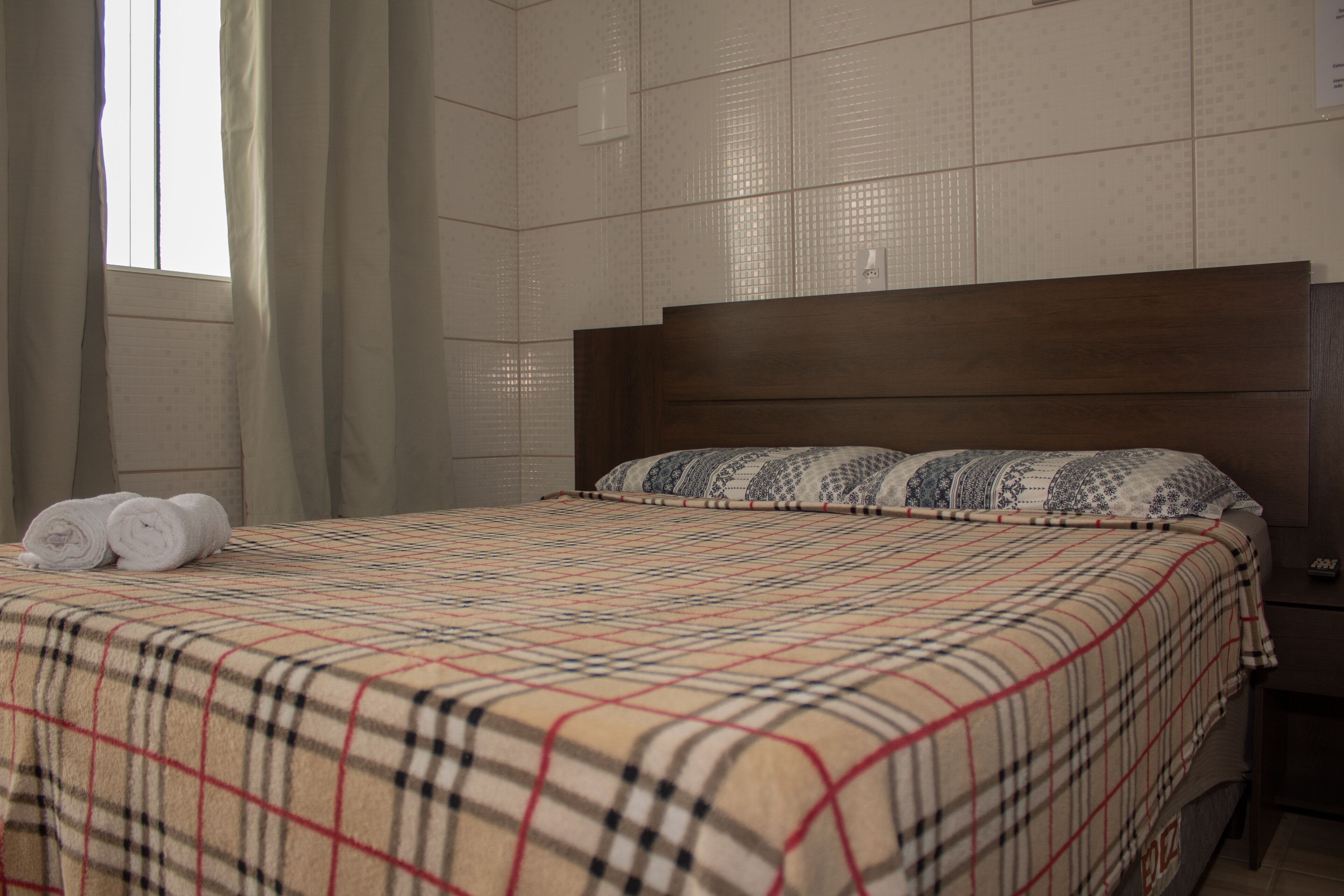 Una habitación de hotel con una cama grande, un cabecero de madera y una ventana con cortinas.