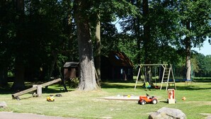 Un parque con un columpio, una estructura de madera y un edificio pequeño.