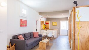 A modern living room with a grey sofa, a wooden coffee table, and a dining area with a white table and chairs.