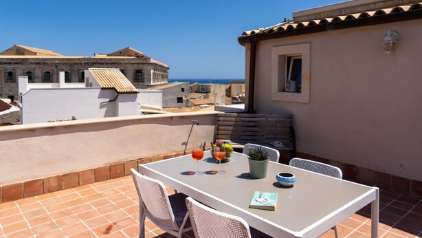 A terrace with a table, chairs, and a potted plant.