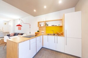 A modern kitchen with white cabinets, a wooden countertop, and a yellow shelf.