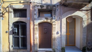A building with a brown door, a window with bars, and a yellow gate.