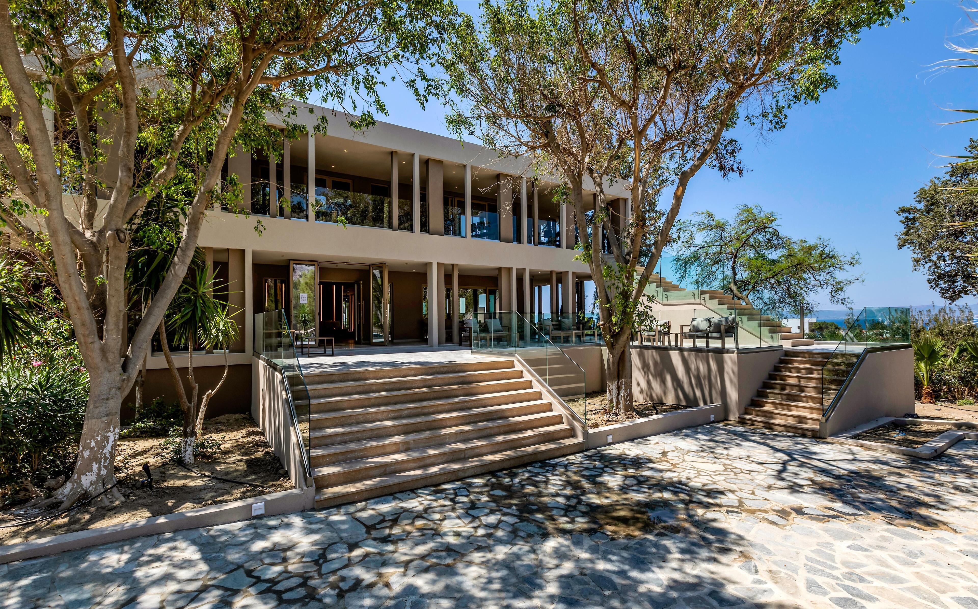 A modern building with a two-story structure, outdoor seating area, and a staircase leading to the entrance.