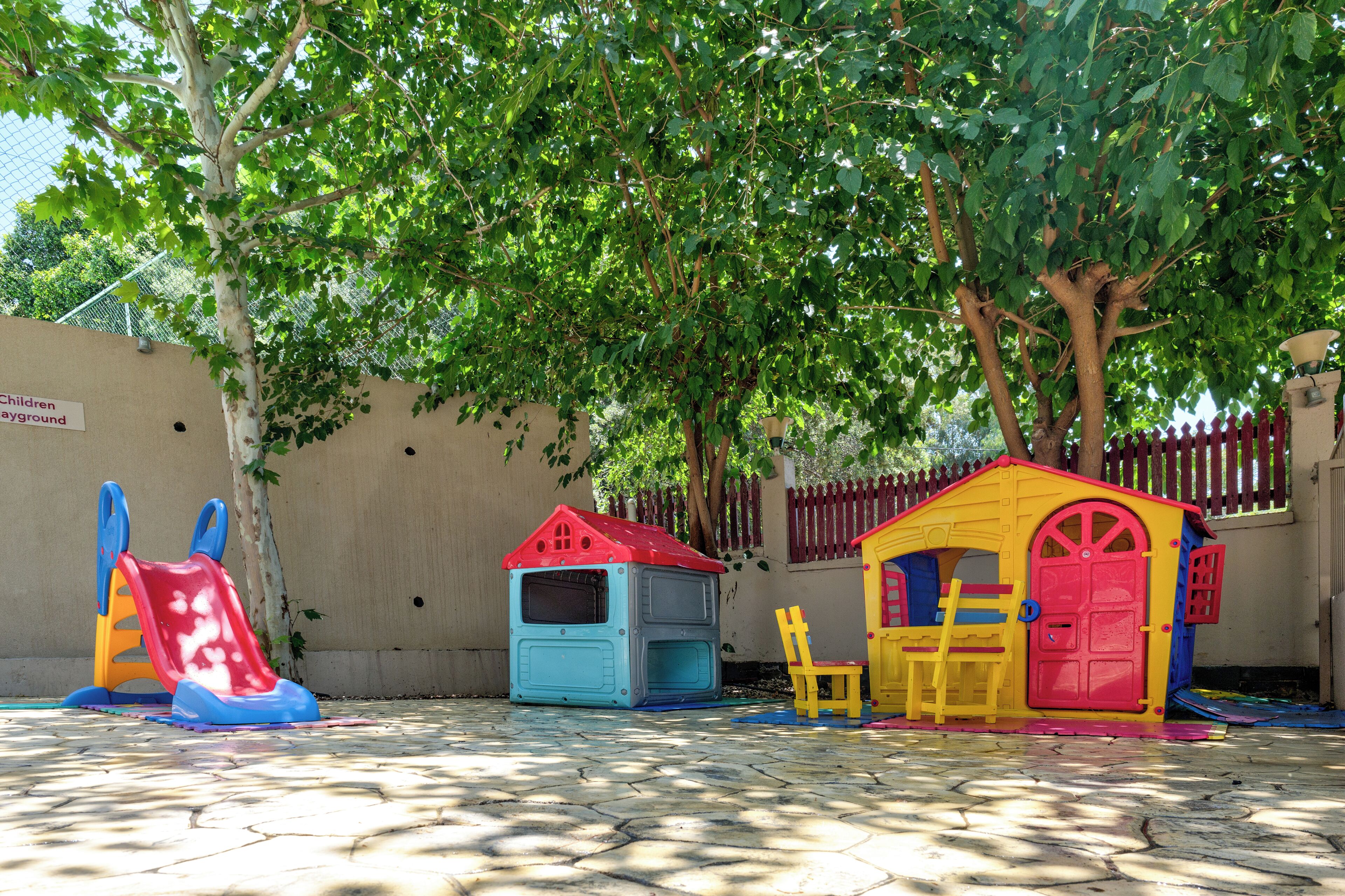 A children's play area with a slide, a playhouse, and a bench.