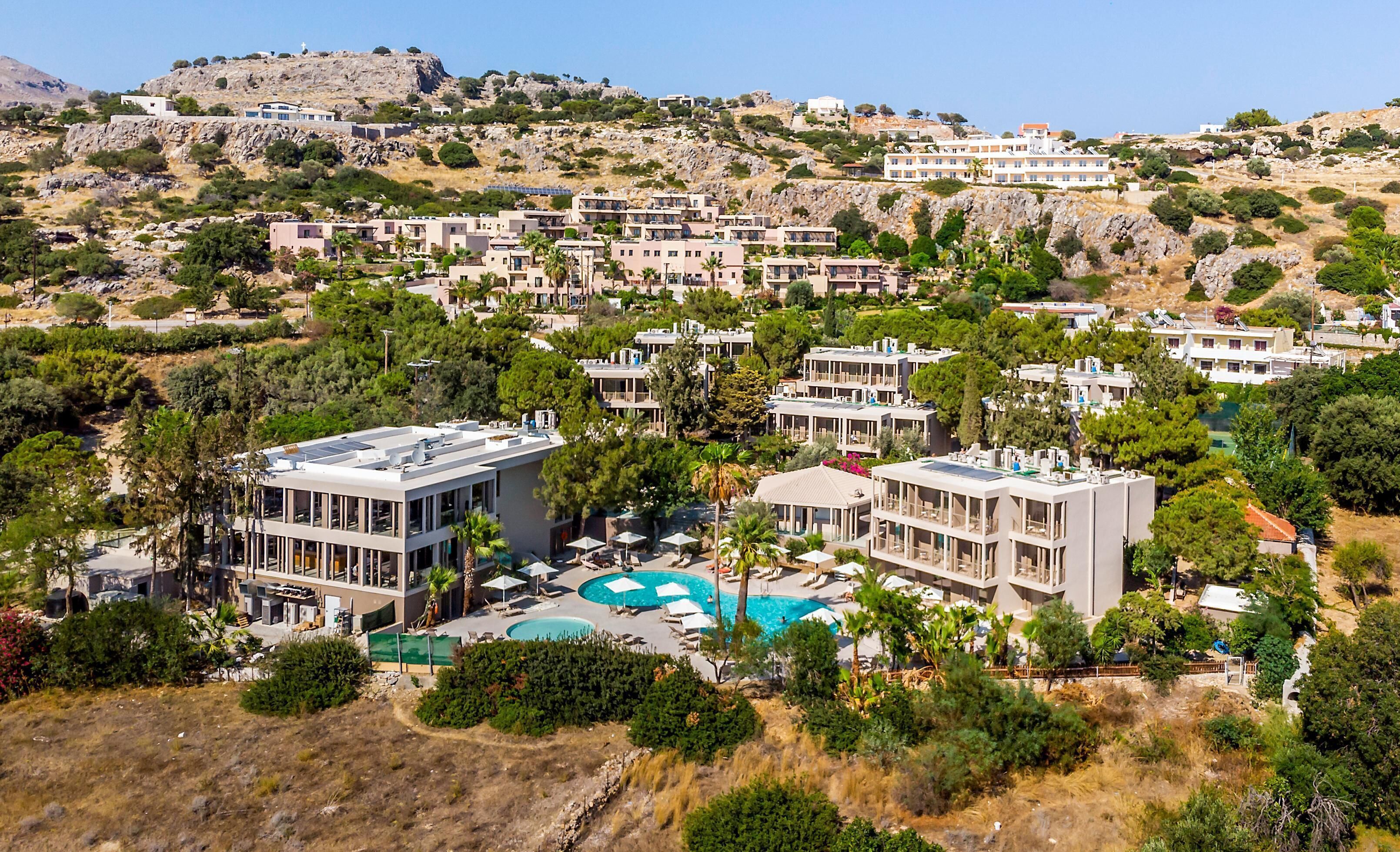 Un resort costero con villas modernas, una piscina y abundante vegetación.