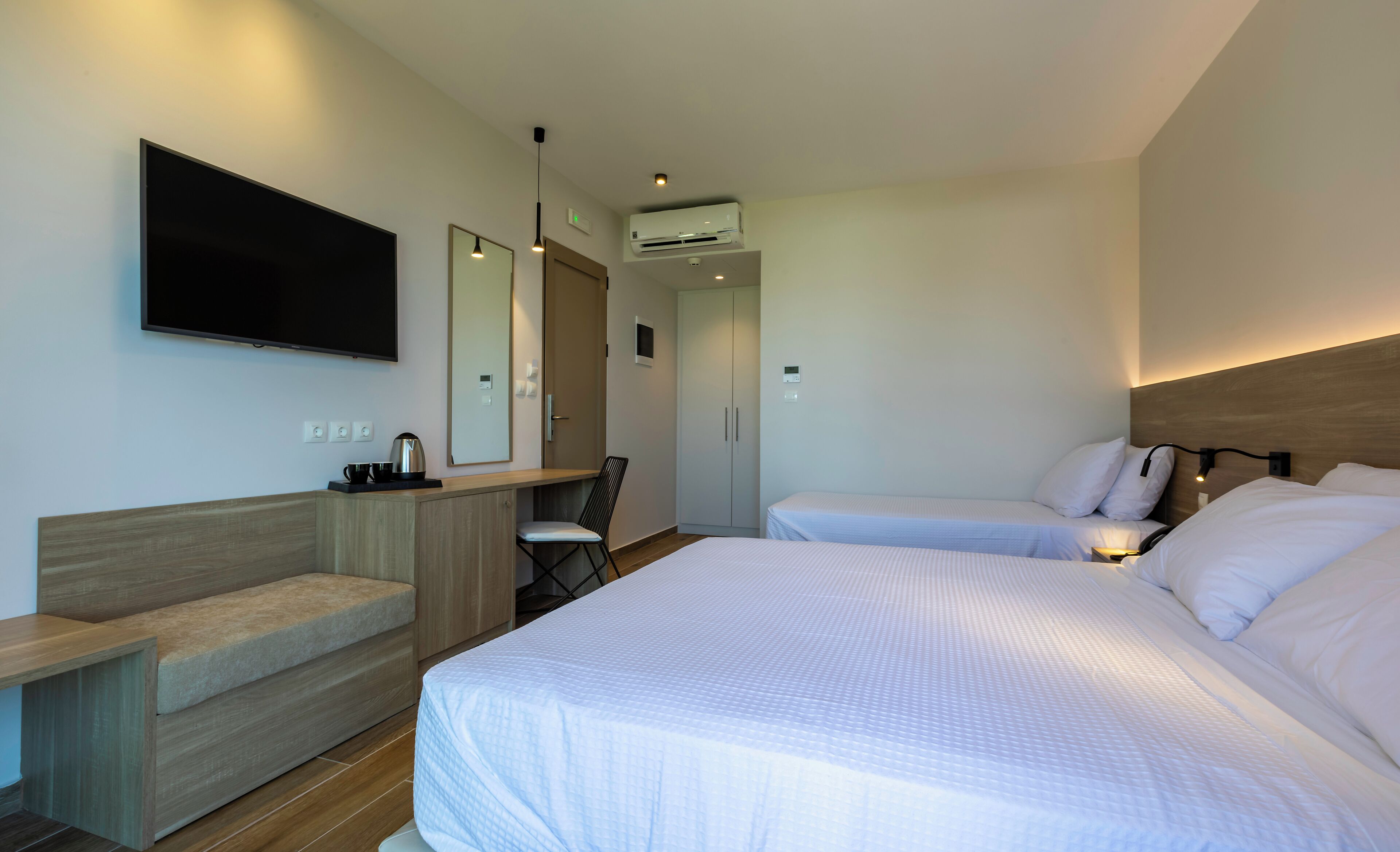 Una habitación de hotel moderna con una cama grande, un escritorio, una silla, un televisor y un armario.