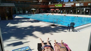 Un área de piscina con tabla de clavados, sillas de descanso y un deck de azulejos.