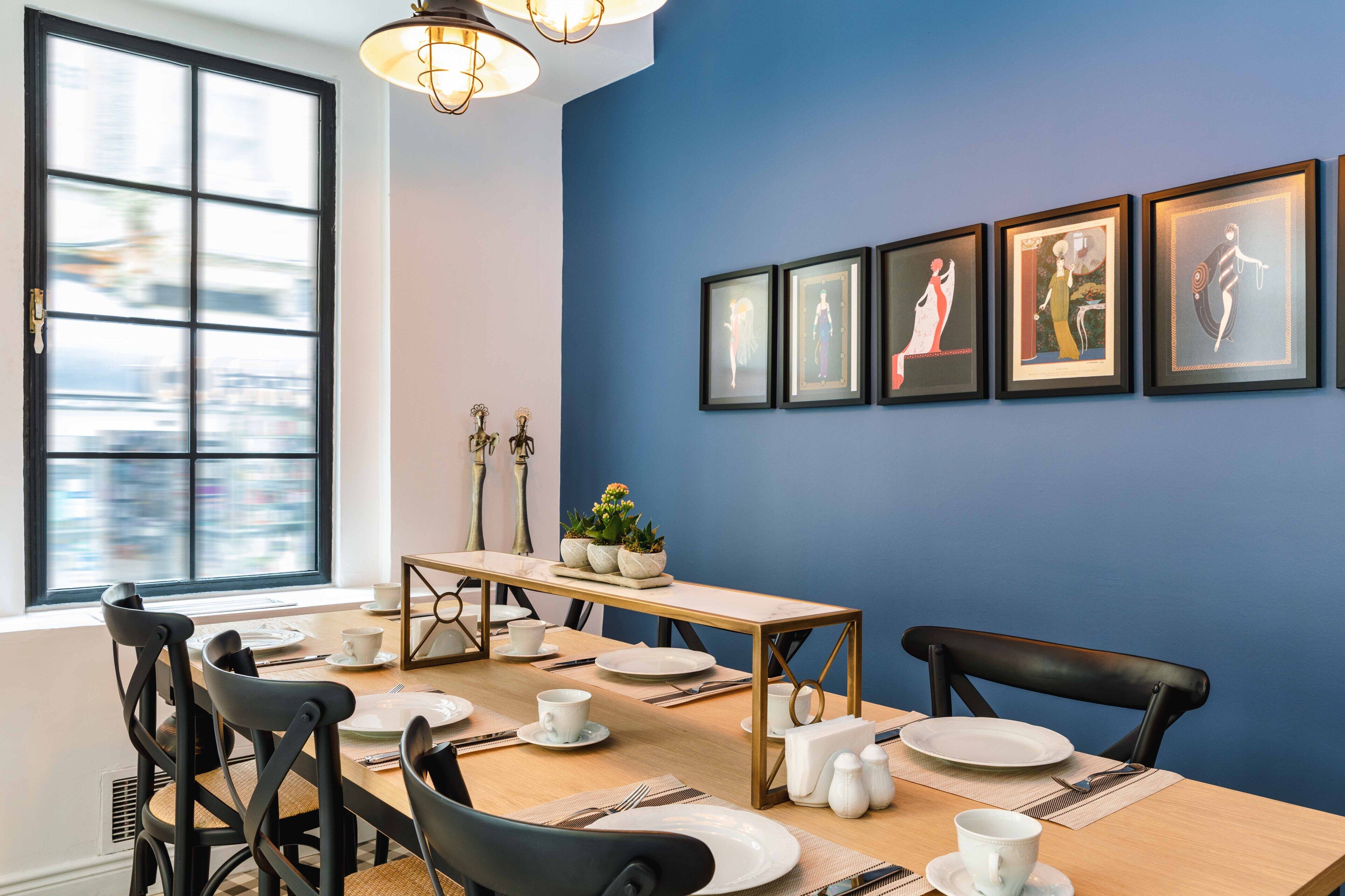 A dining area with a table set for four, chairs, a window with a view, and framed artwork on the wall.