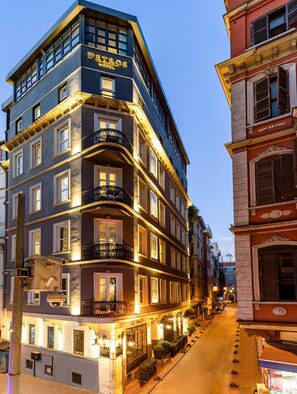 Ein mehrstöckiges Hotel im klassisch europäischen Stil mit Balkonen und einer gut beleuchteten Fassade.