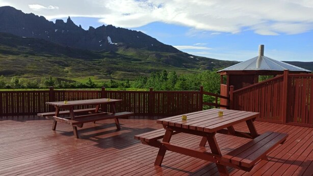A wooden deck with picnic tables and a gazebo overlooking a mountainous landscape. - Engimýri Lodge (Bakki)