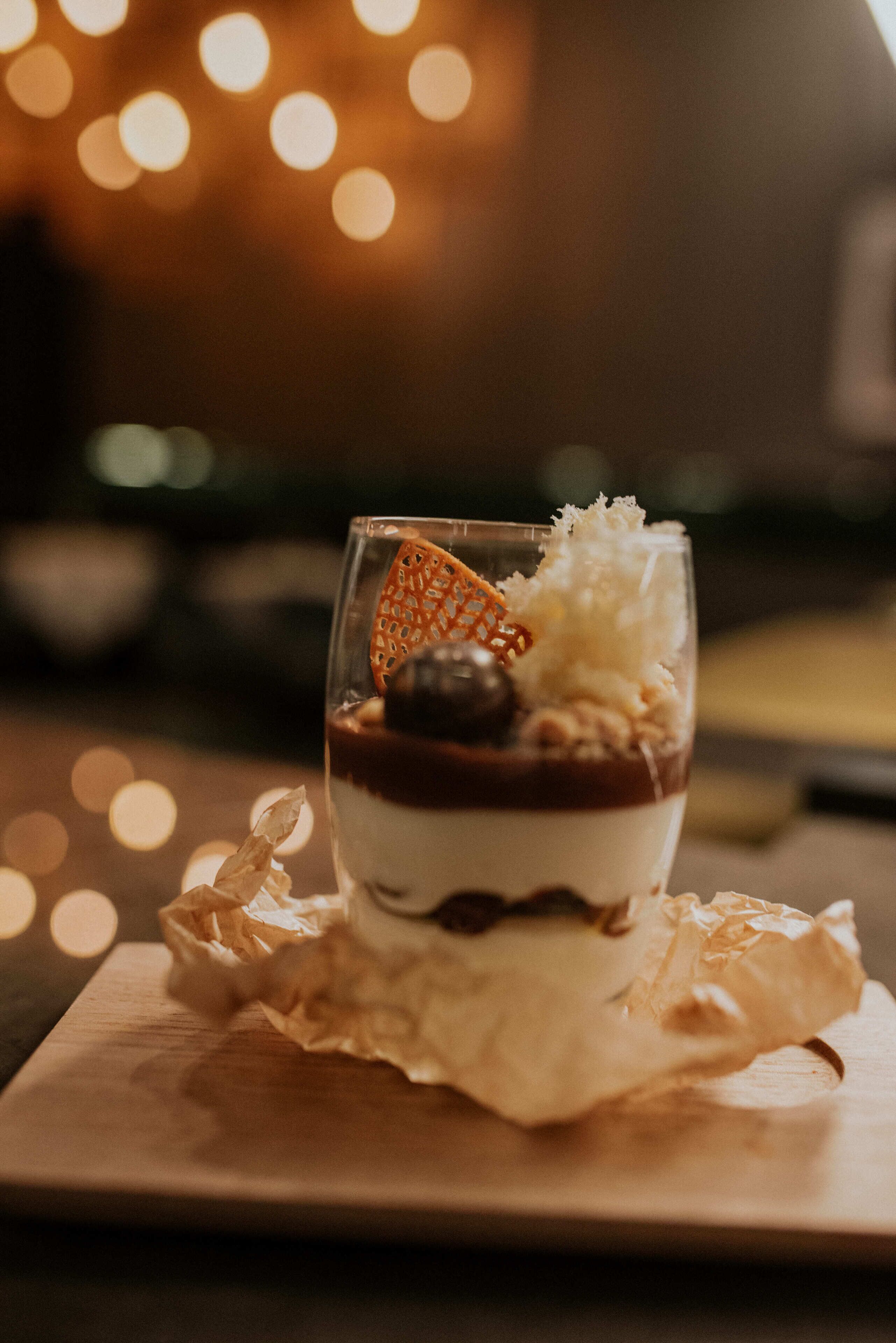 Postre en un vaso sobre una tabla de madera con papel arrugado debajo.
