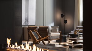 Een moderne woonkamer met een open haard, twee banken, een salontafel en een vloerlamp.