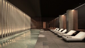 Een modern wellnesscentrum met een lang, spiegelend zwembad en rijen ligbedden langs de muren.