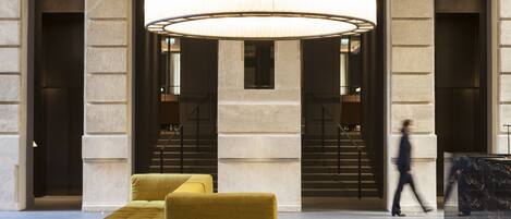 A lobby with a large circular chandelier, a sofa, and a staircase.