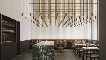 Un interior de restaurante moderno con barra de mármol, detalles dorados colgantes y un diseño limpio y contemporáneo.