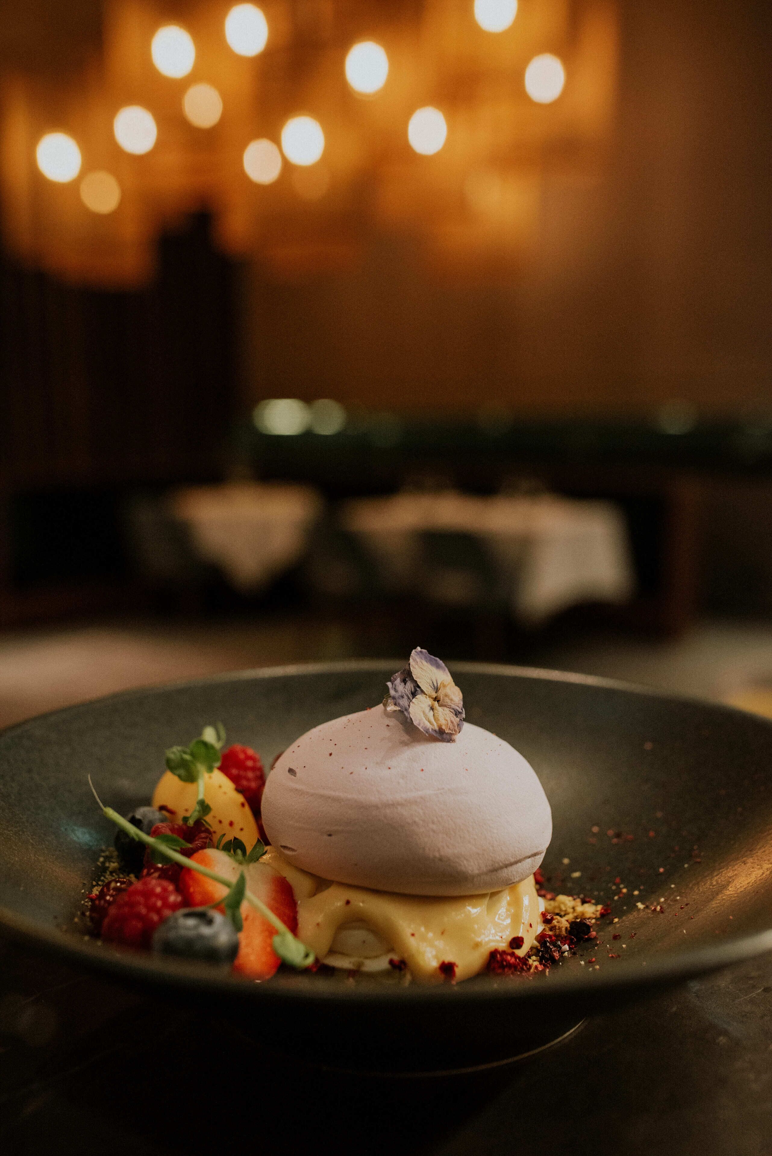 A dessert on a plate with berries and a flower on top.