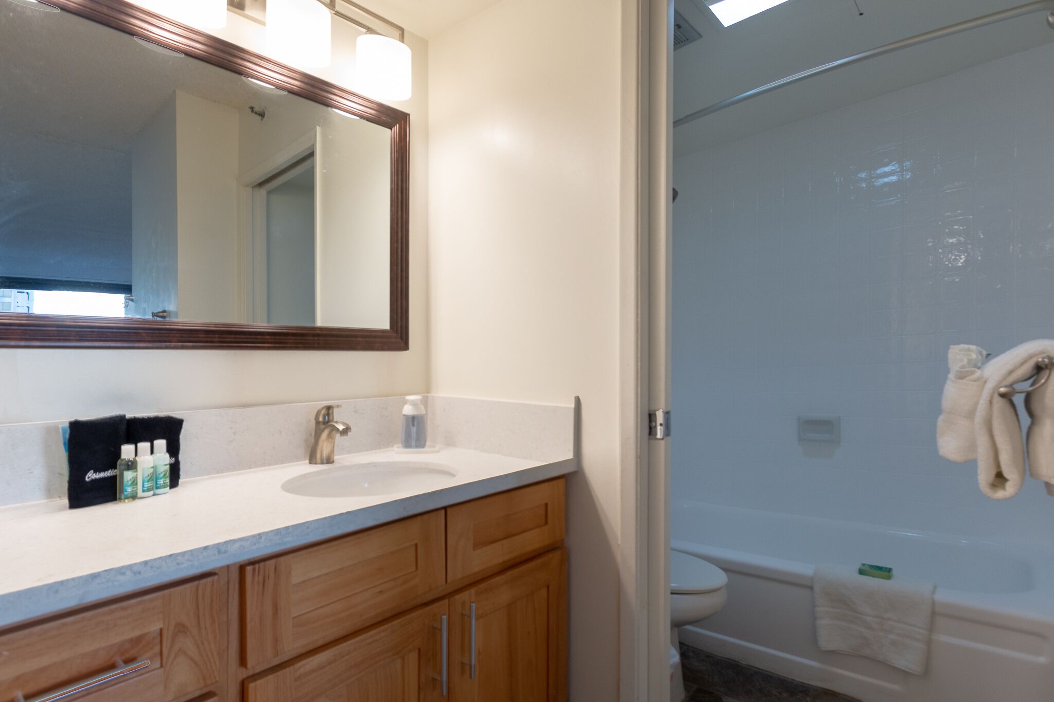 A bathroom with a sink, mirror, and shower.