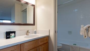 A bathroom with a sink, mirror, and shower.