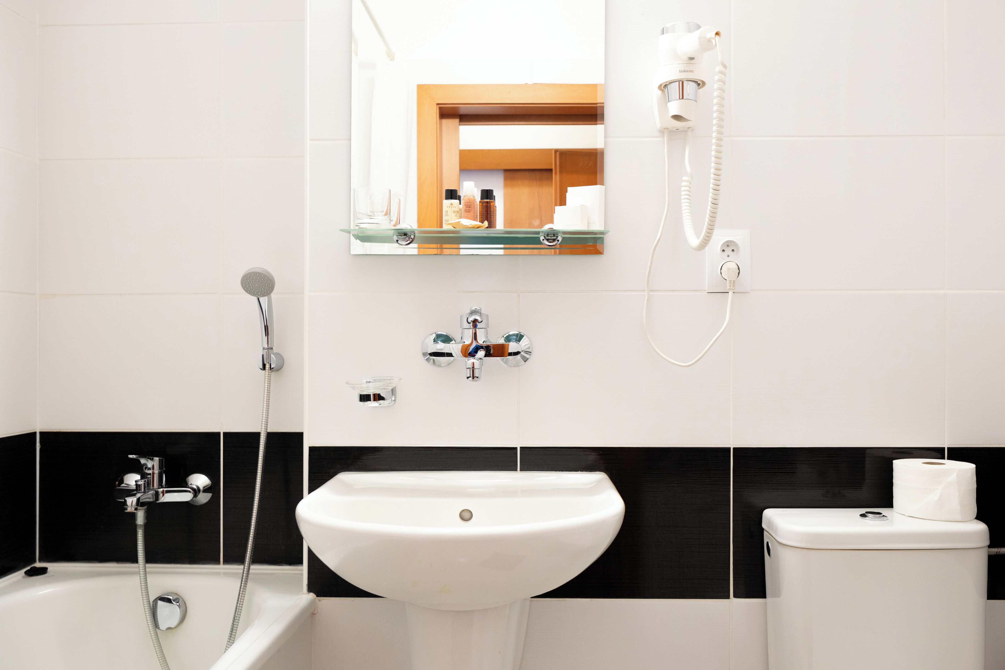 Un baño con un lavabo blanco, una bañera, un inodoro y un espejo sobre el lavabo.
