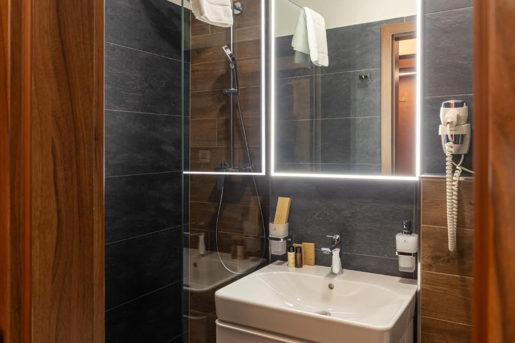 Une salle de bain moderne avec une douche à parois de verre, un lavabo blanc et un miroir.
