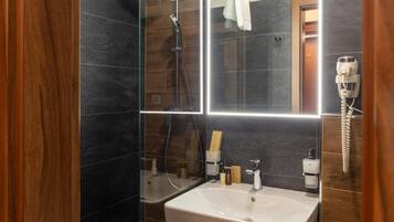 Une salle de bain moderne avec une douche à parois de verre, un lavabo blanc et un miroir.