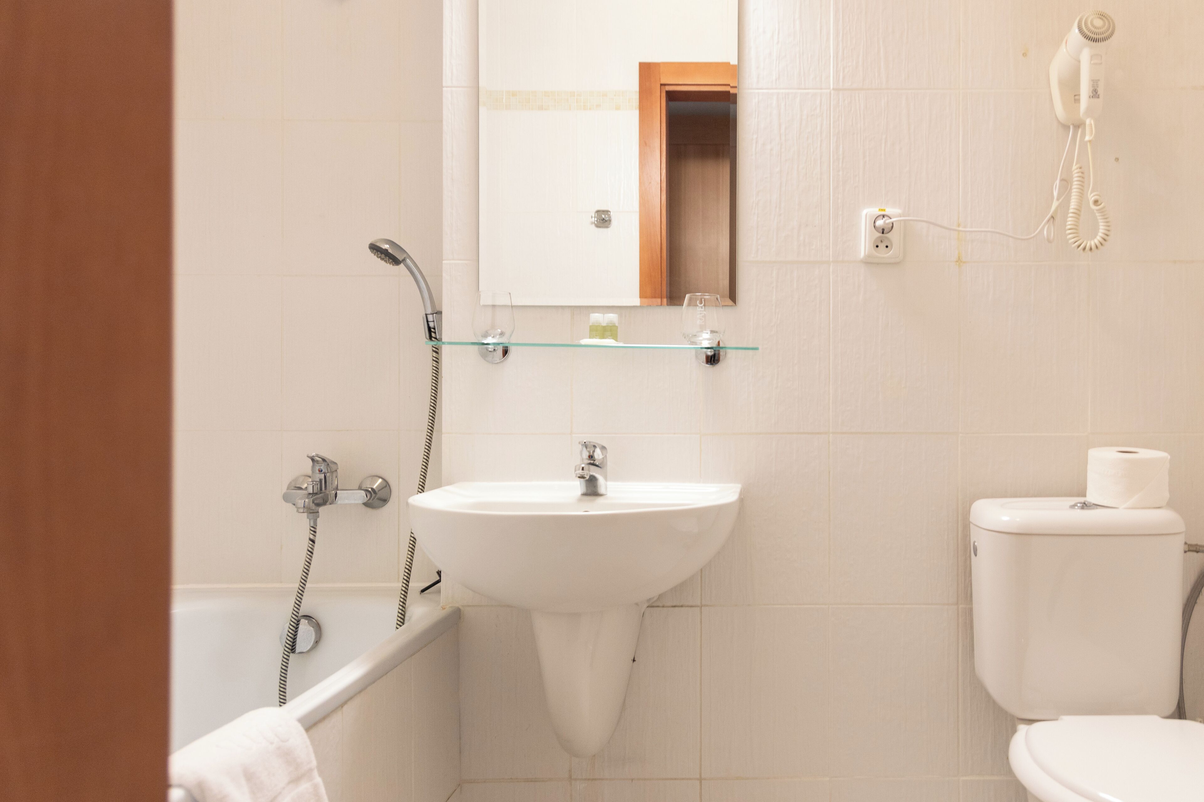 Ein Badezimmer mit einem weißen Waschbecken, einem Spiegel, einer Toilette und einer Dusche.