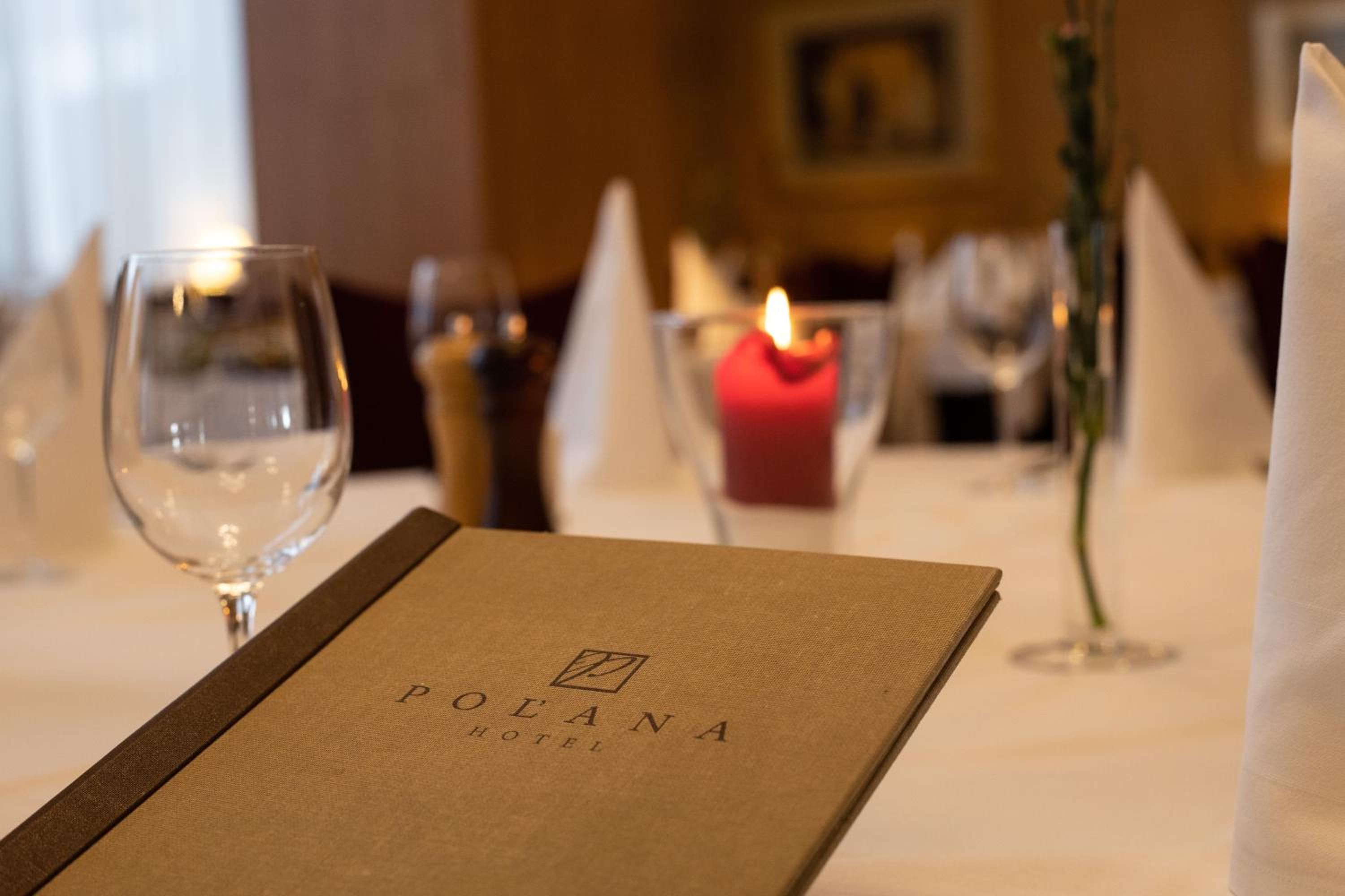 A menu with the text 'POLANA HOTEL' on a table set for dining.
