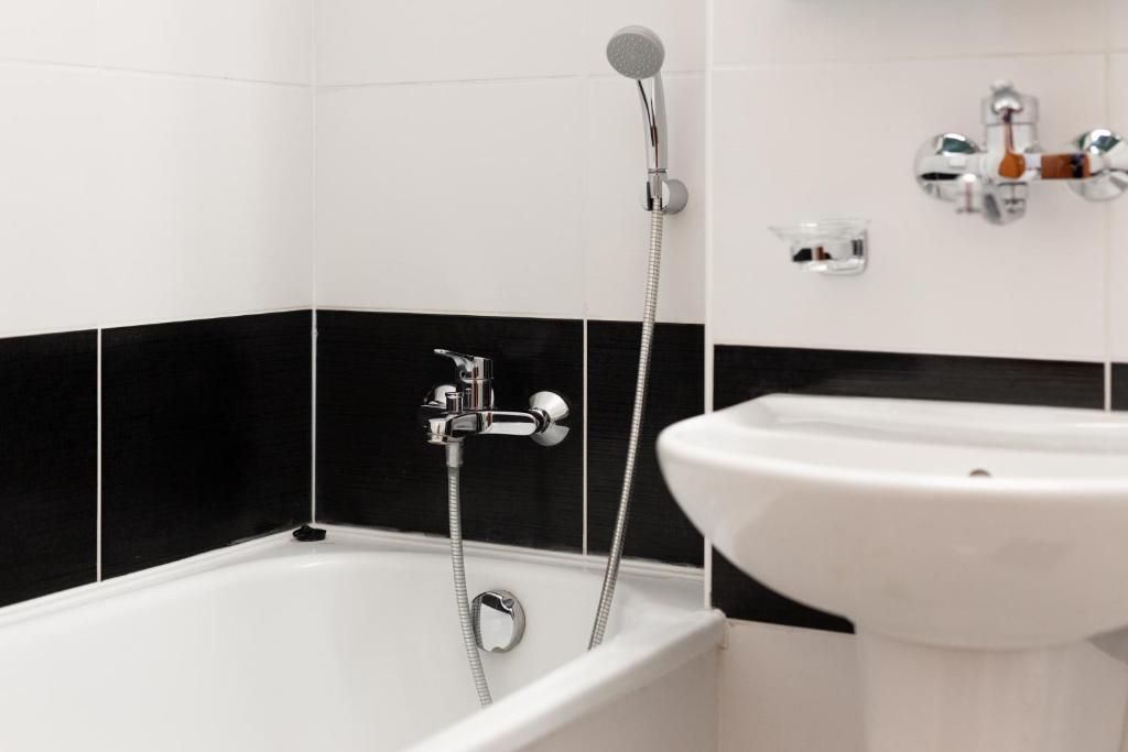 A bathroom with a bathtub, a showerhead, and a sink.