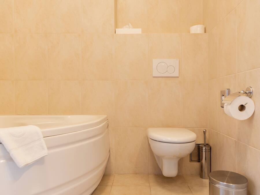 Ein Badezimmer mit Badewanne, Toilette und Mülleimer.