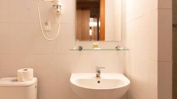Ein Badezimmer mit Toilette, Waschbecken, Spiegel und Wandhaartrockner.