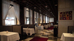 Een restaurant met zitjes en tafels, geruite vloer en een rood tapijt.