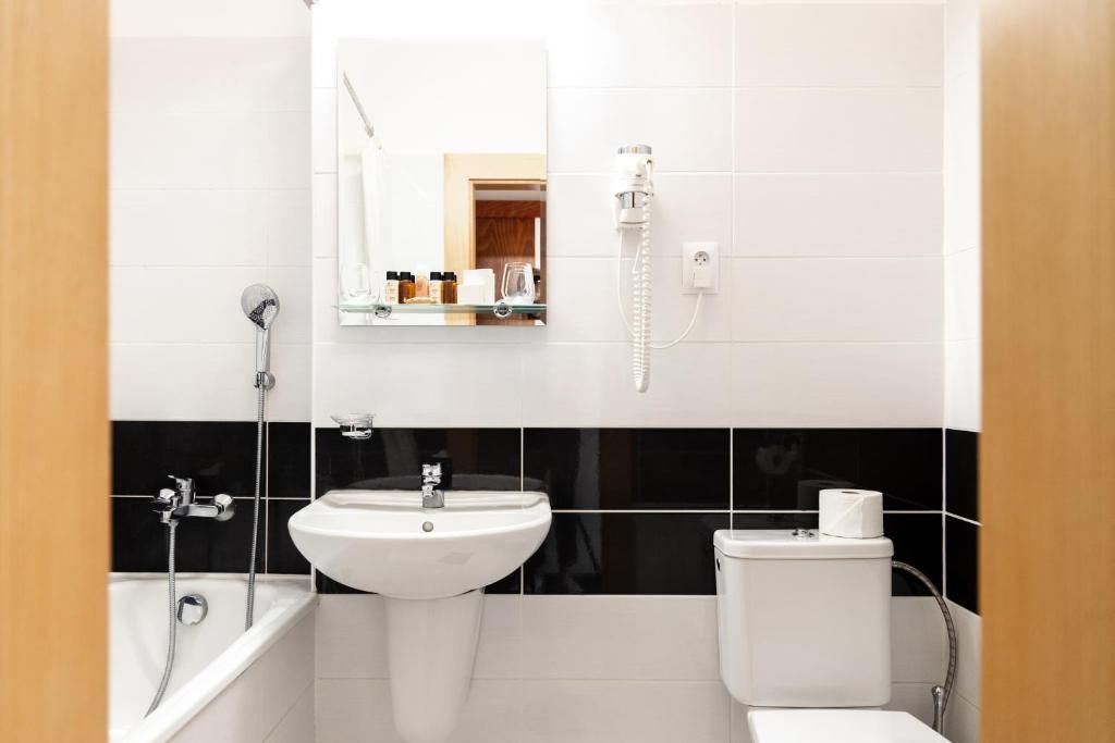 A bathroom with a white sink, a mirror, a toilet, and a shower.
