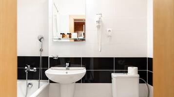 A bathroom with a white sink, a mirror, a toilet, and a shower.