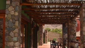 Un edificio de piedra con una pérgola de madera y un patio.