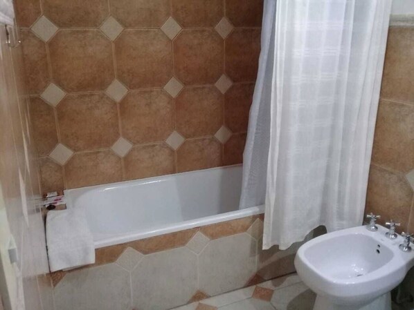 A bathroom with a bathtub, a bidet, and hexagonal patterned tiles. - El Refugio de Coquena (Purmamarca)