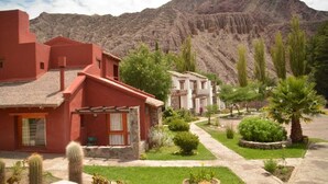 Un edificio rojo con techo de paja, un edificio blanco con varias ventanas, y una montaña al fondo.